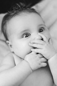 A baby with hands over its mouth